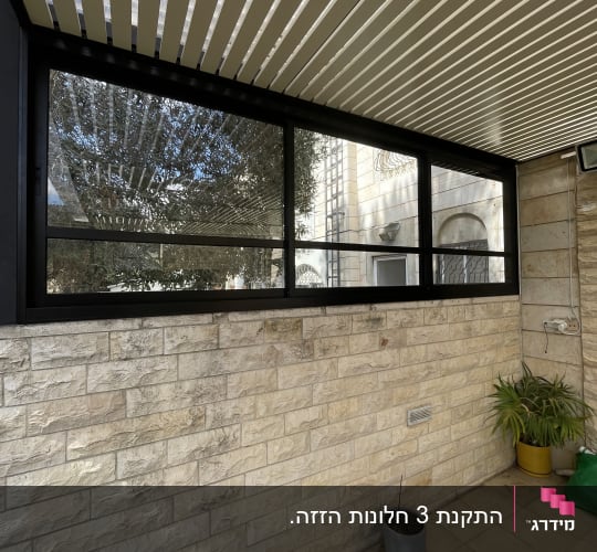 חלון אלומיניום עם מסגרת שחורה וקיר לבנים